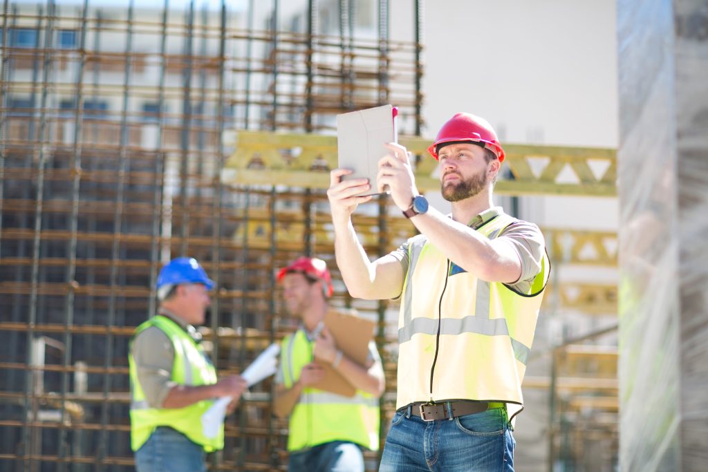 construction worker performing digital safety inspection on construction site using tablet