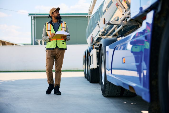 HGV driver carrying out a daily driver walkaround check next to a tanker truck