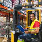 Forklift operator completing a daily forklift inspection checklist in a warehouse before shift start