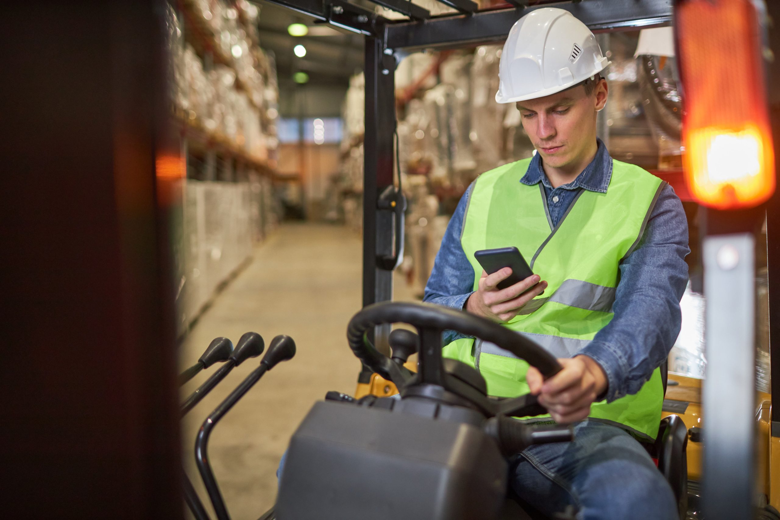 Forklift driver completing a digital pre-use forklift inspection checklist on a mobile phone