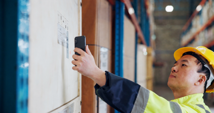 Construction worker in hi-vis scanning a tool asset label with a phone to track every asset