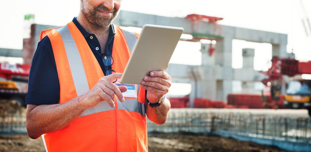 Site manager in a hi-vis vest using a tablet on a construction site