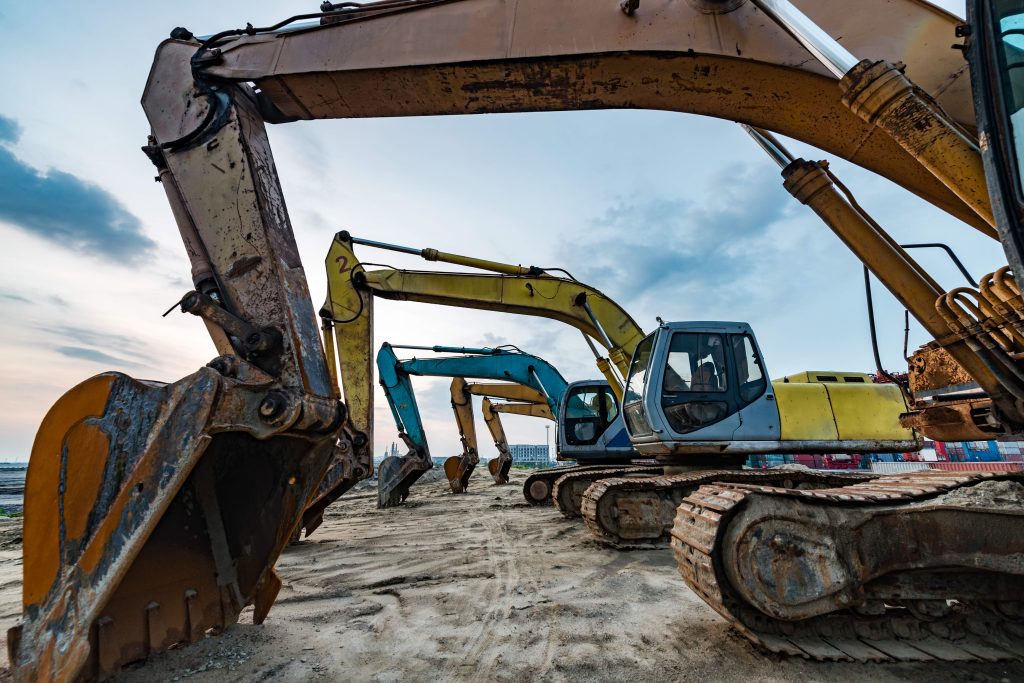 Excavators parked in a row at a plant hire yard at dusk