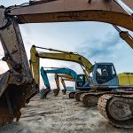 Excavators parked in a row at a plant hire yard at dusk