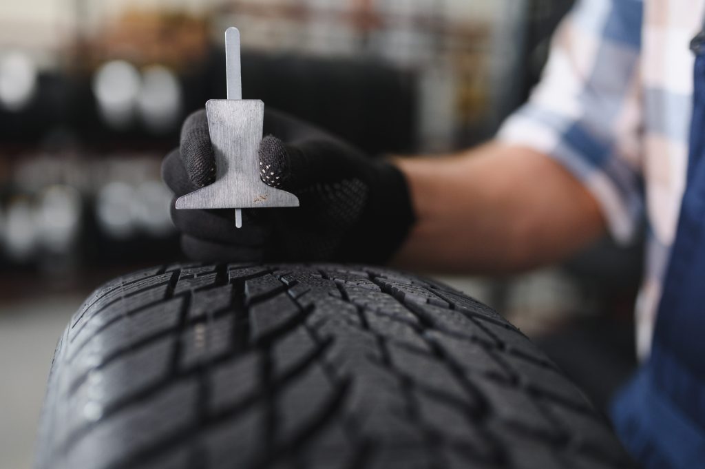 Tread depth gauge being used to measure tyre tread in a workshop