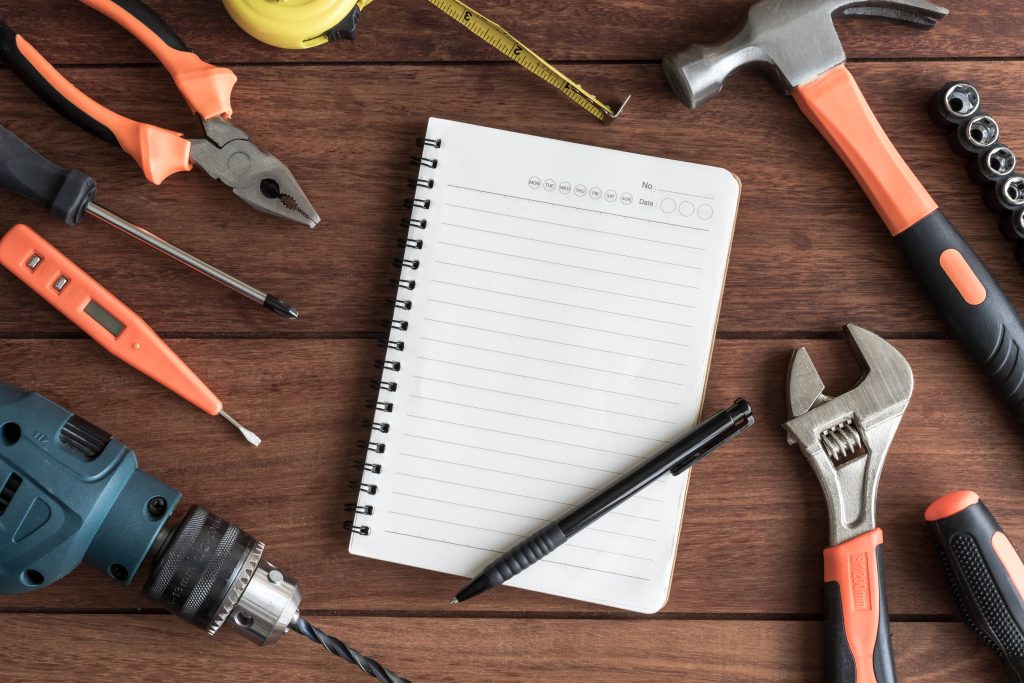 Blank weekly planner notebook surrounded by hand tools on a workbench